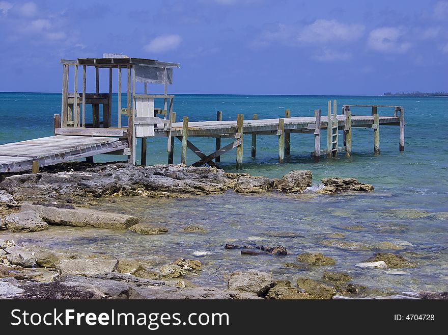 A fishing dock juts out from a rocky shore on a distant Caribbean isle. A fishing dock juts out from a rocky shore on a distant Caribbean isle.