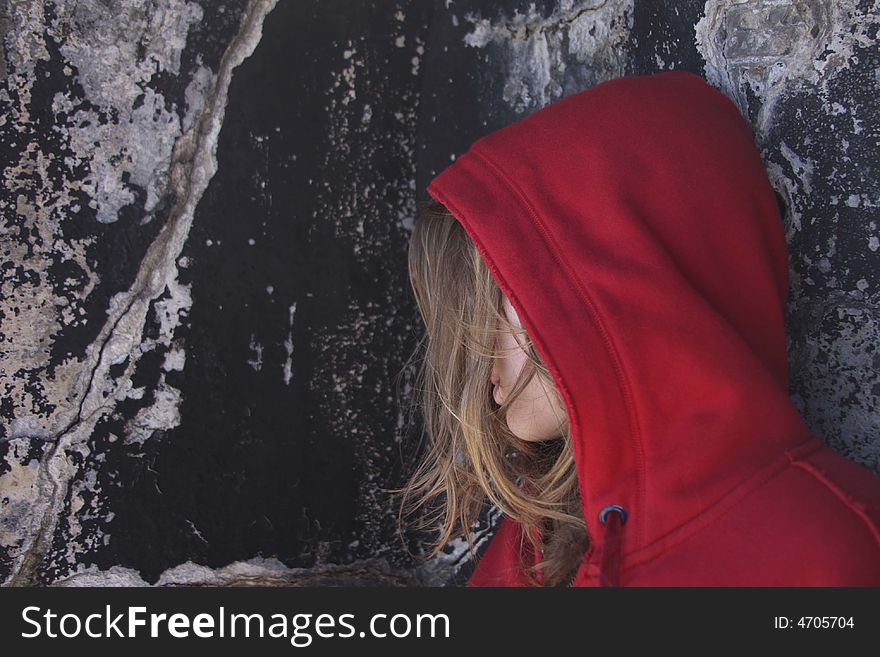 Girl in red hood leaning on ancient wall. Girl in red hood leaning on ancient wall