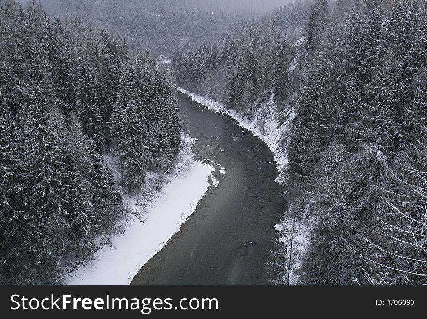 Bird's eye view on the river En (Inn) and a forest covered with snow, snowy weather. Scuol, Switzerland. Bird's eye view on the river En (Inn) and a forest covered with snow, snowy weather. Scuol, Switzerland