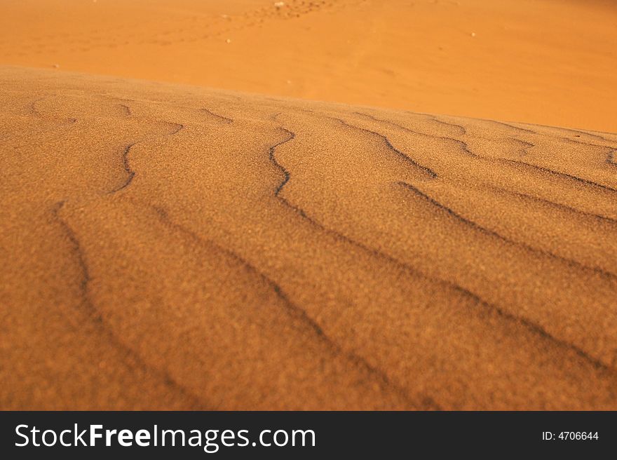 A sandy desert dune with footsteps on the back.