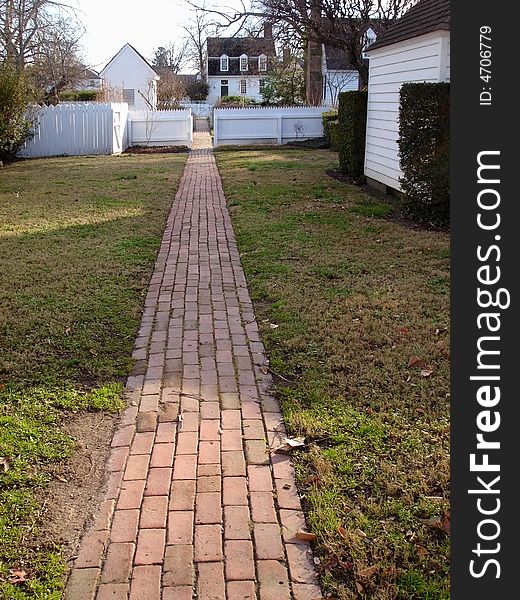 A red brick walkway leading to a small village