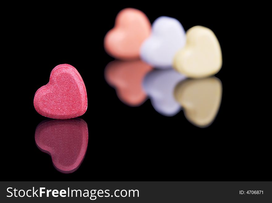 Red candy heart with a few more candy hearts in the background out of focus.