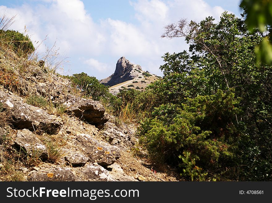 Mountain peak among white clouds on the blue sky