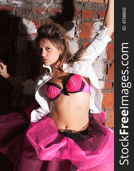 Sexy girl in pink bra and skirt on brick wall background. Sexy girl in pink bra and skirt on brick wall background