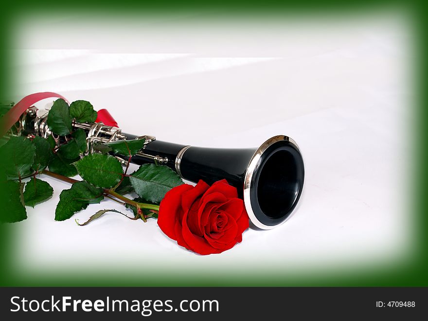 Red rose and black clarinet composition over white in green frame. Red rose and black clarinet composition over white in green frame