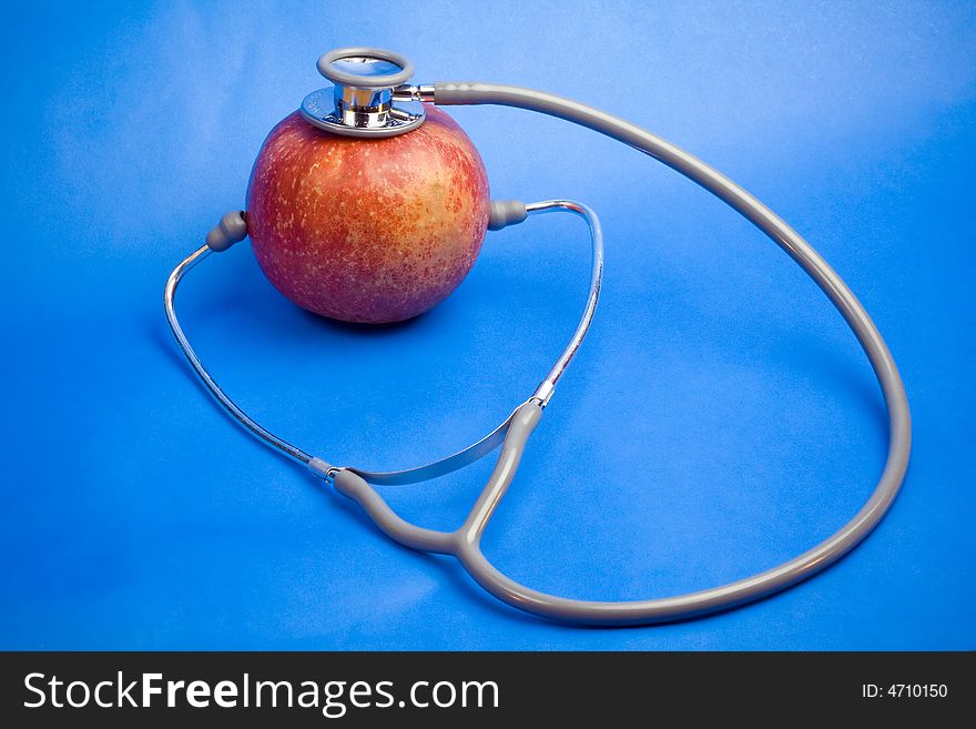 Red apple with stethotoscope isolated on blue background