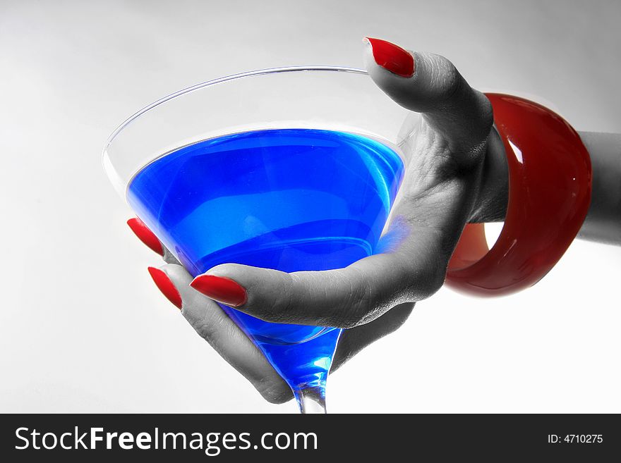 A female hand is holding blue coctail and giving. A female hand is holding blue coctail and giving