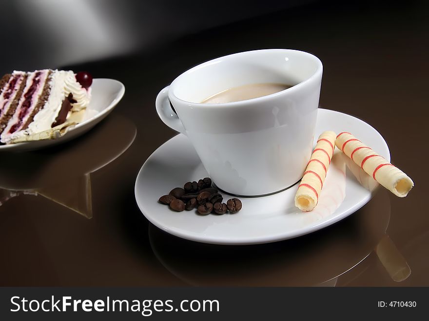 Cup of coffee with two rolls and piece of cake standing on the table