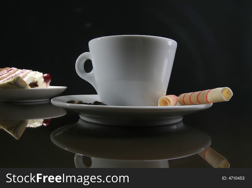 Cup of coffee with two rolls and piece of cake in background. Cup of coffee with two rolls and piece of cake in background