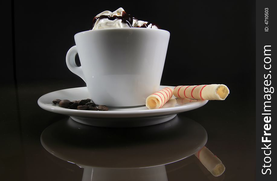 A cup of coffee with two rolls on the black background. A cup of coffee with two rolls on the black background