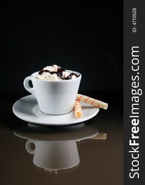 A cup of coffee with two rolls on the black background. A cup of coffee with two rolls on the black background