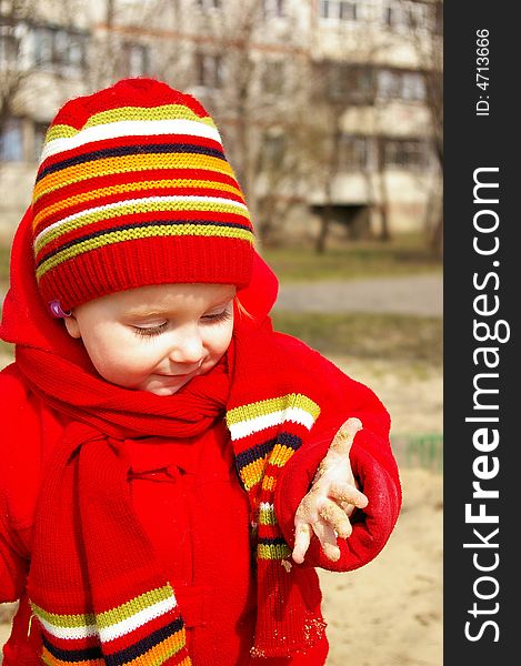 Little girl in the bright cap and  scarf play with sand. Little girl in the bright cap and  scarf play with sand