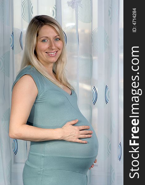 Smiling pregnant woman standing and looking at camera