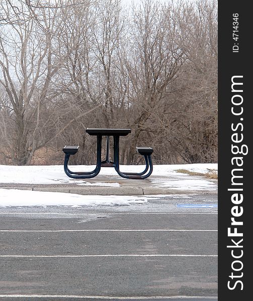 A picture of a solitary picnic table in the woods in early spring. A picture of a solitary picnic table in the woods in early spring