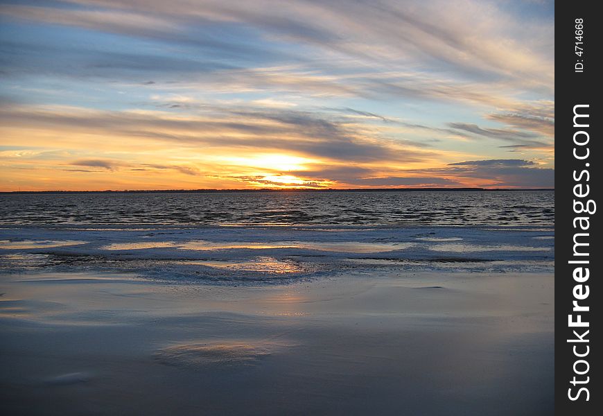 Sunset over ice river in autumn