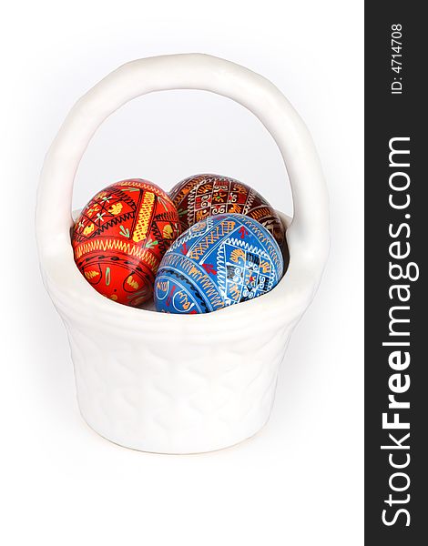 Three easter eggs in white basket over white