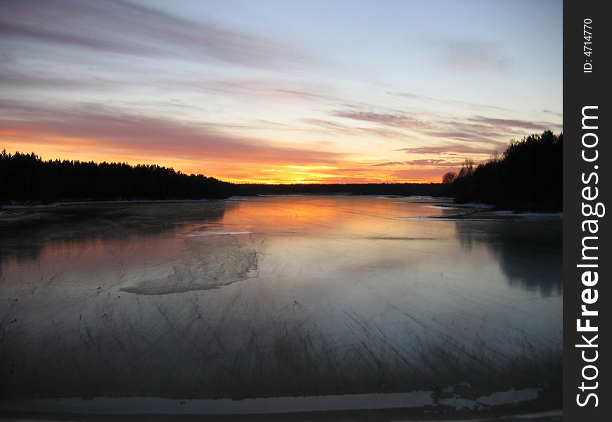 Sunset over ice river in autumn