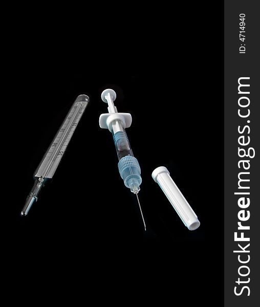 Medical syringe and thermometer isolated on black background
