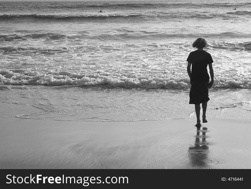 Teenage boy walking out to the ocean tide. Teenage boy walking out to the ocean tide.