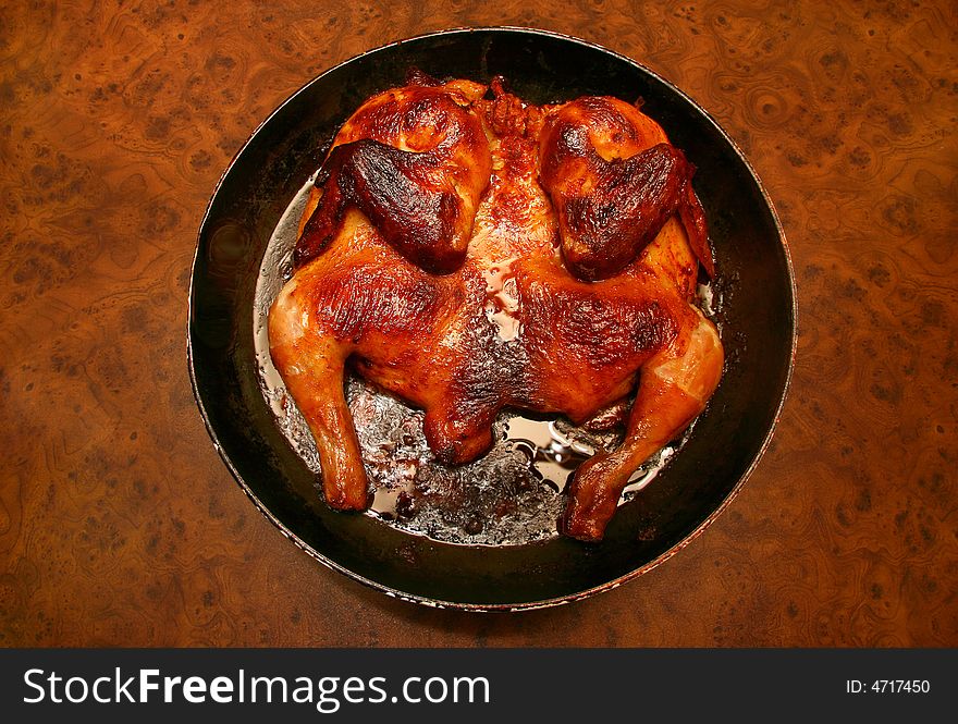 Frying pan with the fried hen on a table. Frying pan with the fried hen on a table.