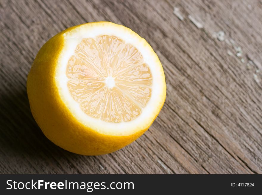 Half of sour yellow lemon laying on the old wooden table. Half of sour yellow lemon laying on the old wooden table