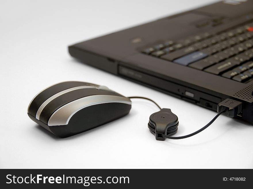 Modern black notebook computer on white background with computer mouse