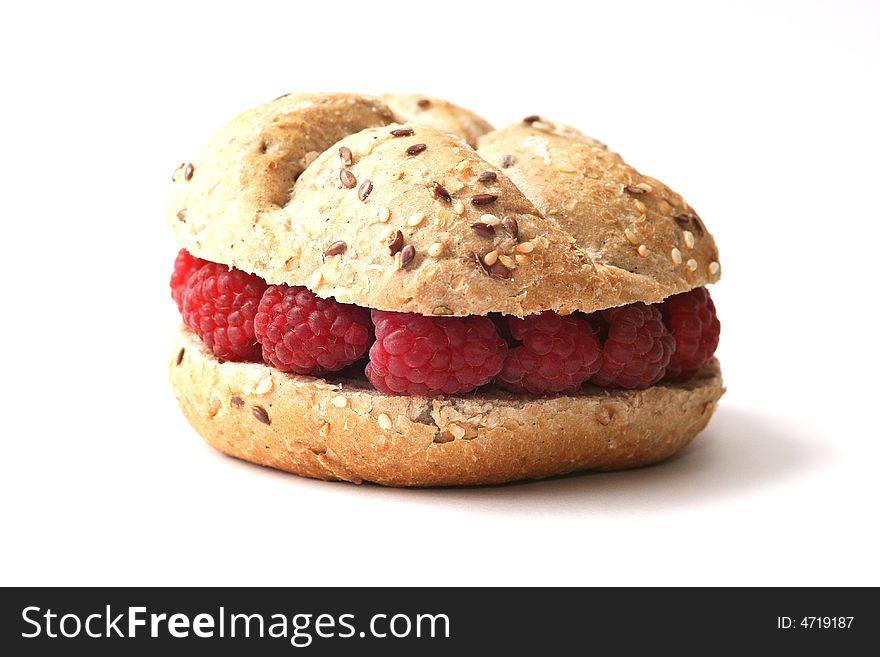 Fresh baked whole grain roll with raspberry on white background.