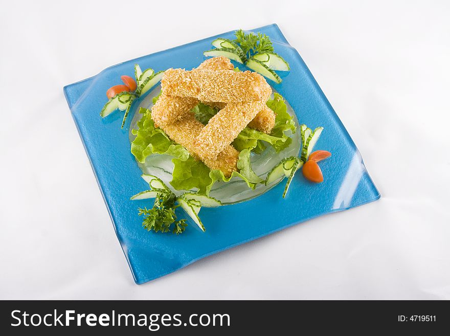 Crispy meat sticks with vegetables on a blue square plate set on a white background.
