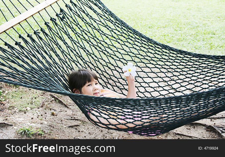Girl with flower swinging in hammock. Girl with flower swinging in hammock
