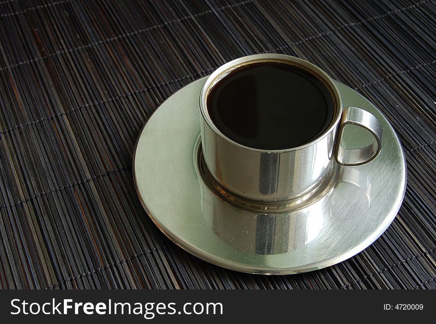 A cup of coffee on a black bamboo background. A cup of coffee on a black bamboo background
