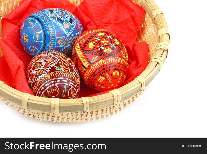 Three russian tradition easter eggs in yellow basket close up over white