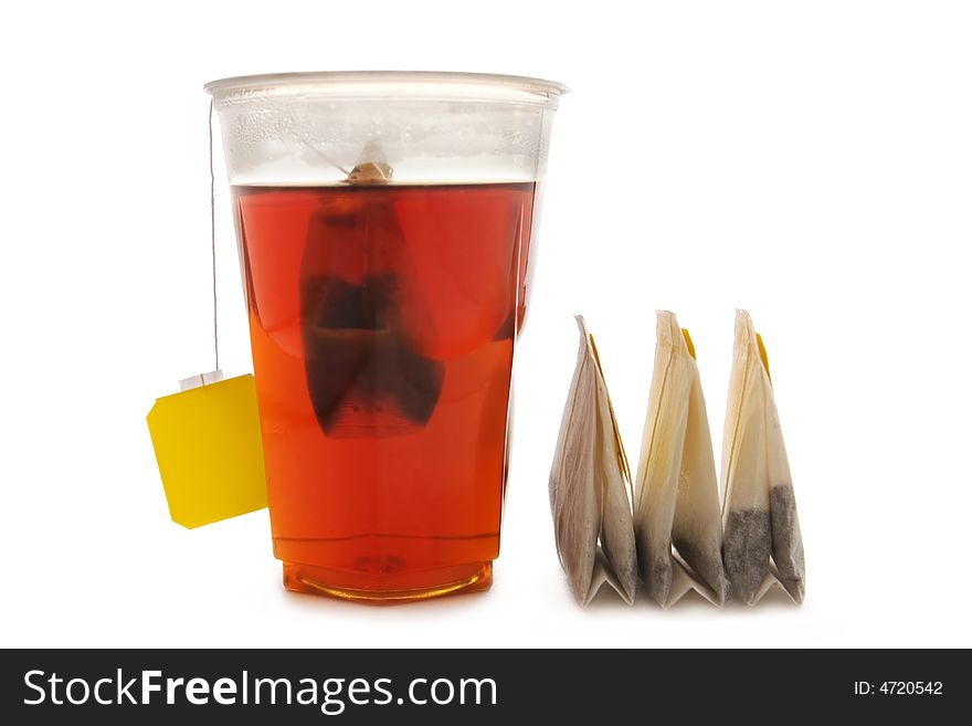 Three tea bags and plastic glass with tea