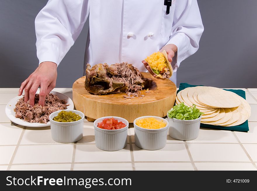 Close up portrait of a uniformed female Chef preparing a juicy pork roast soft shell taco. Close up portrait of a uniformed female Chef preparing a juicy pork roast soft shell taco.