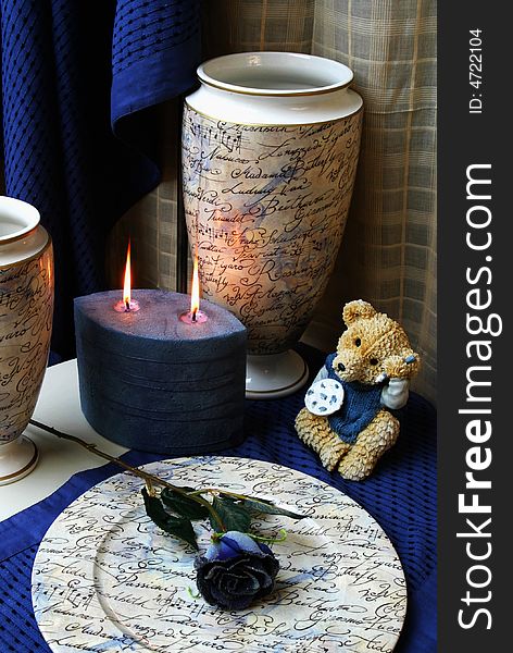 Decorative still-life with a candle, rose and bear in blue. Decorative still-life with a candle, rose and bear in blue.