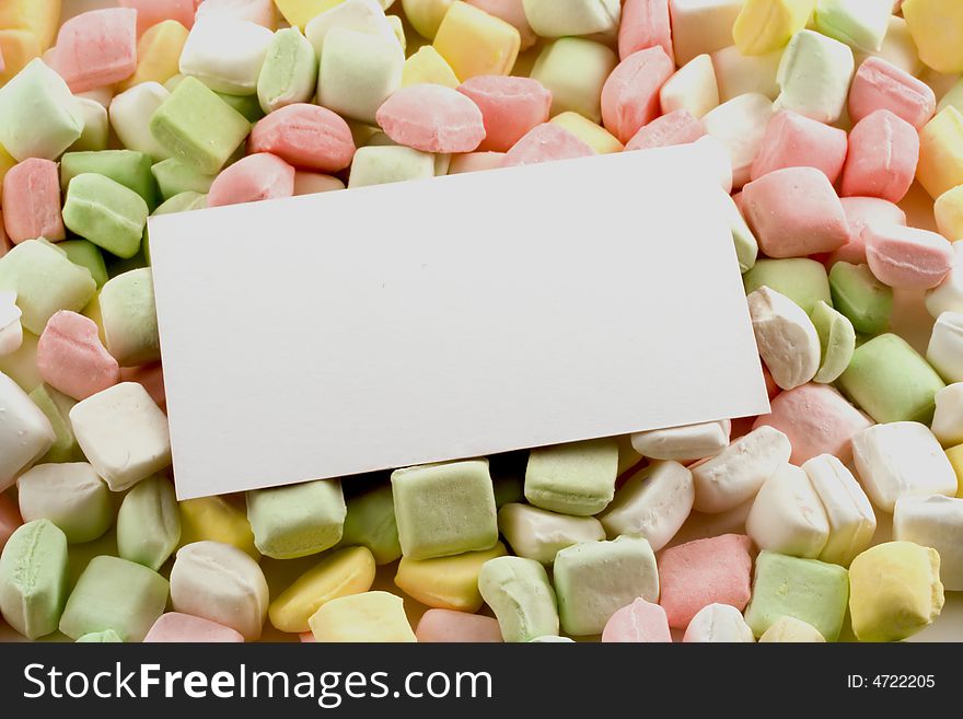 A bed of pastel dinner mints support a white business card. A bed of pastel dinner mints support a white business card.