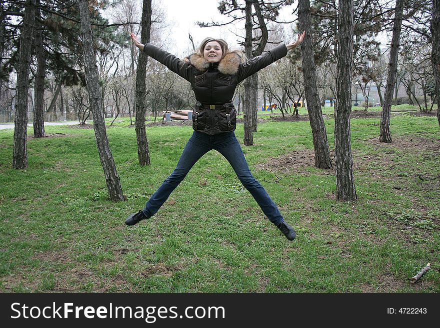 Cheerful smiling girl jump in the meadow