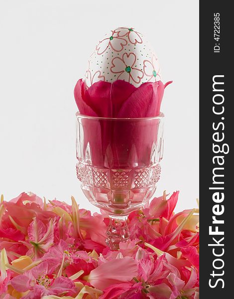 A hand decorated Easter egg rests inside a tulip which in turn rests inside a crystal cup. A hand decorated Easter egg rests inside a tulip which in turn rests inside a crystal cup.