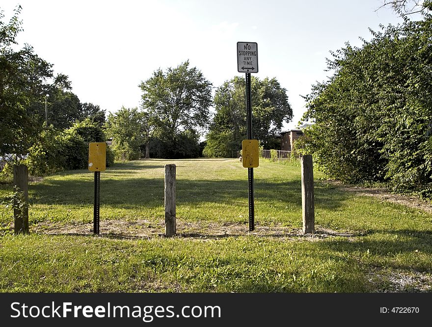 A no parking sign and barriers leading to a park area. A no parking sign and barriers leading to a park area.