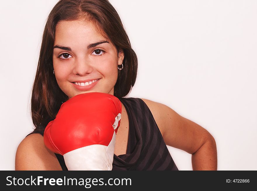 Healthy young woman in red boxing gloves stands smiling with gloves under her chin, her guard up at a cardio boxing workout. Healthy young woman in red boxing gloves stands smiling with gloves under her chin, her guard up at a cardio boxing workout.