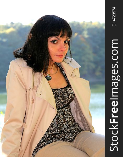 Beautiful woman sitting on the boulder in front of the lake. Beautiful woman sitting on the boulder in front of the lake