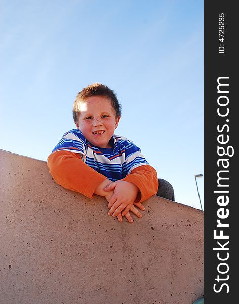 Young boy on top of a rock climbing wall with hands crossed. Young boy on top of a rock climbing wall with hands crossed