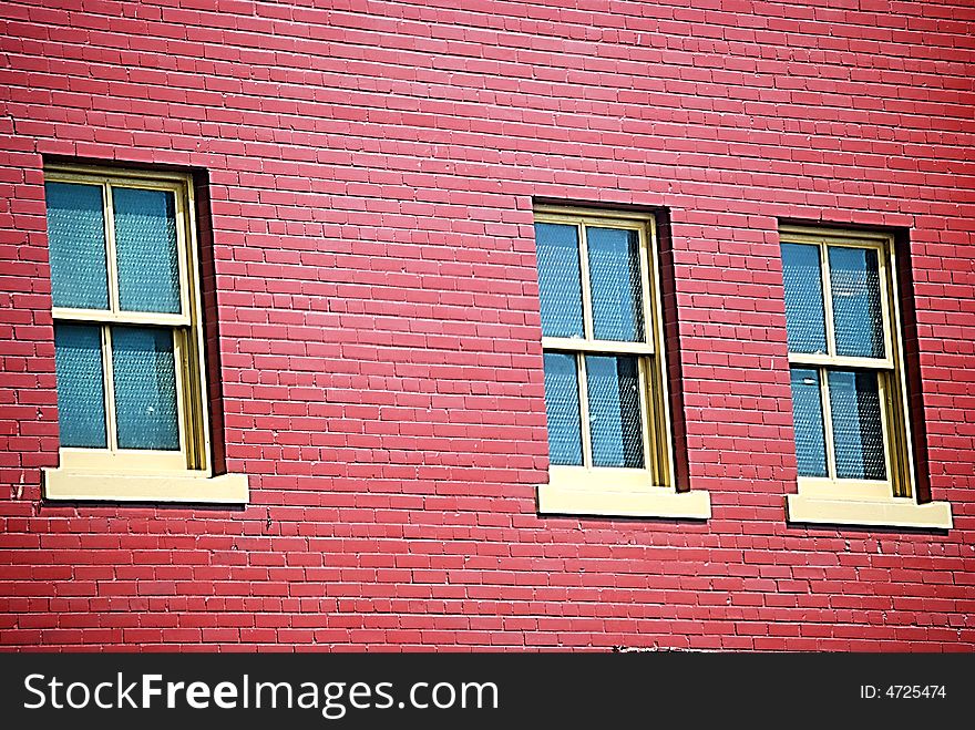 A red brick wall with three windows. A red brick wall with three windows.