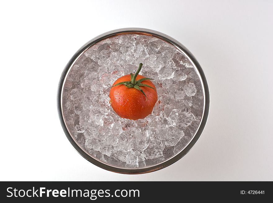 Bright red tomato resting in metal bowl of ice isolated on white. Bright red tomato resting in metal bowl of ice isolated on white