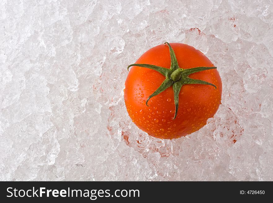 A red ripe tomato kept fresh on a bed of ice. A red ripe tomato kept fresh on a bed of ice.