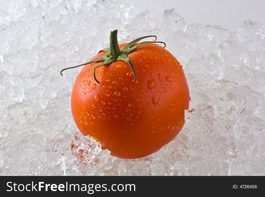 A red ripe tomato kept fresh on a bed of ice. A red ripe tomato kept fresh on a bed of ice.