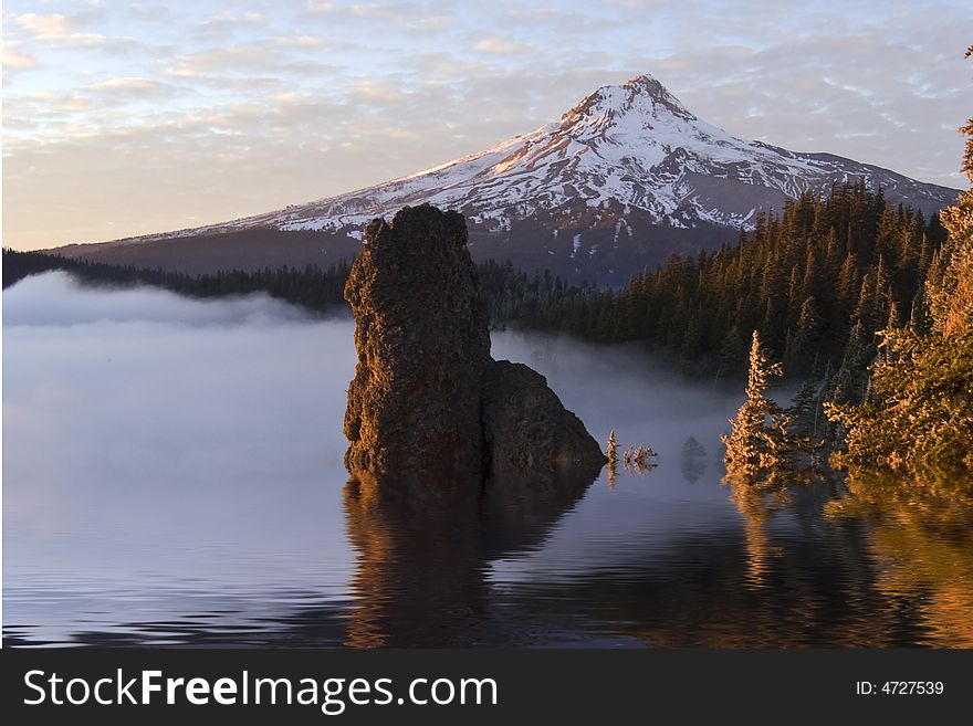 Mountain with simulated flood condition from global warming at sunset with rock coming out of water in foreground at sunset. Mountain with simulated flood condition from global warming at sunset with rock coming out of water in foreground at sunset