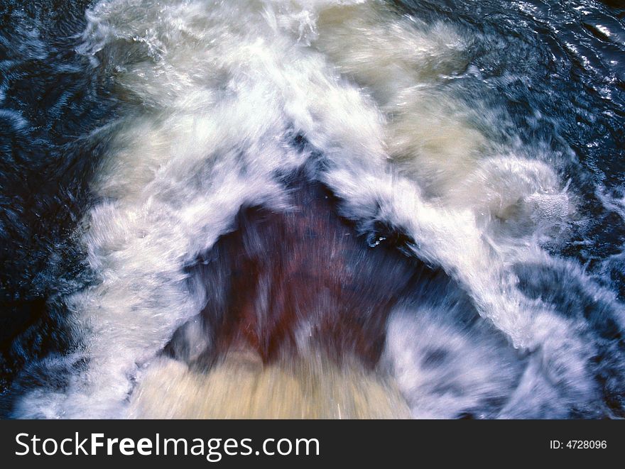 Looking down on a waterfall as it flows into a blue pool of water. Looking down on a waterfall as it flows into a blue pool of water