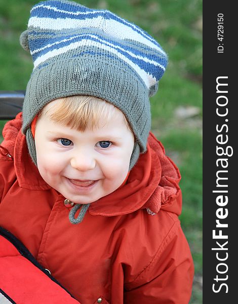 The little boy smiles on a background of a green lawn in the spring. The little boy smiles on a background of a green lawn in the spring