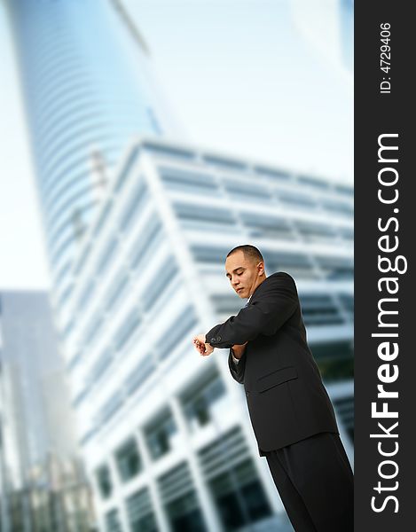 Shot of a man in business suit checking his watch while walking out of his office in downtown area. Shot of a man in business suit checking his watch while walking out of his office in downtown area