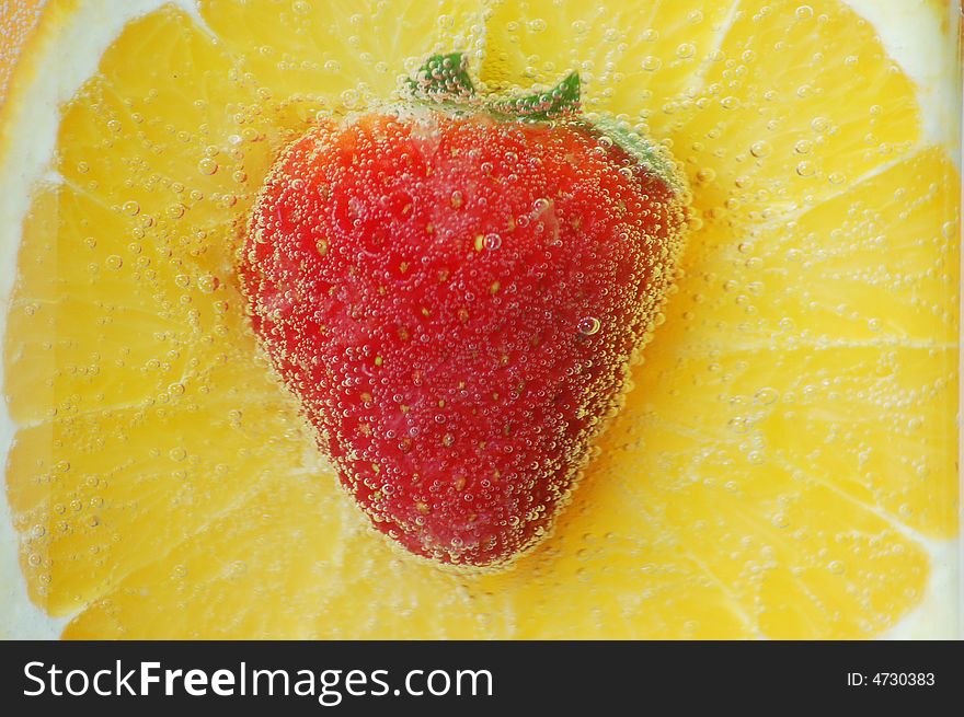 An orange and strawberry in water. An orange and strawberry in water